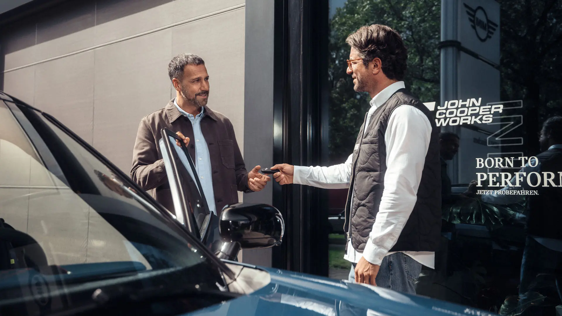 A MINI Partner service advisor hands a vehicle key to a customer.