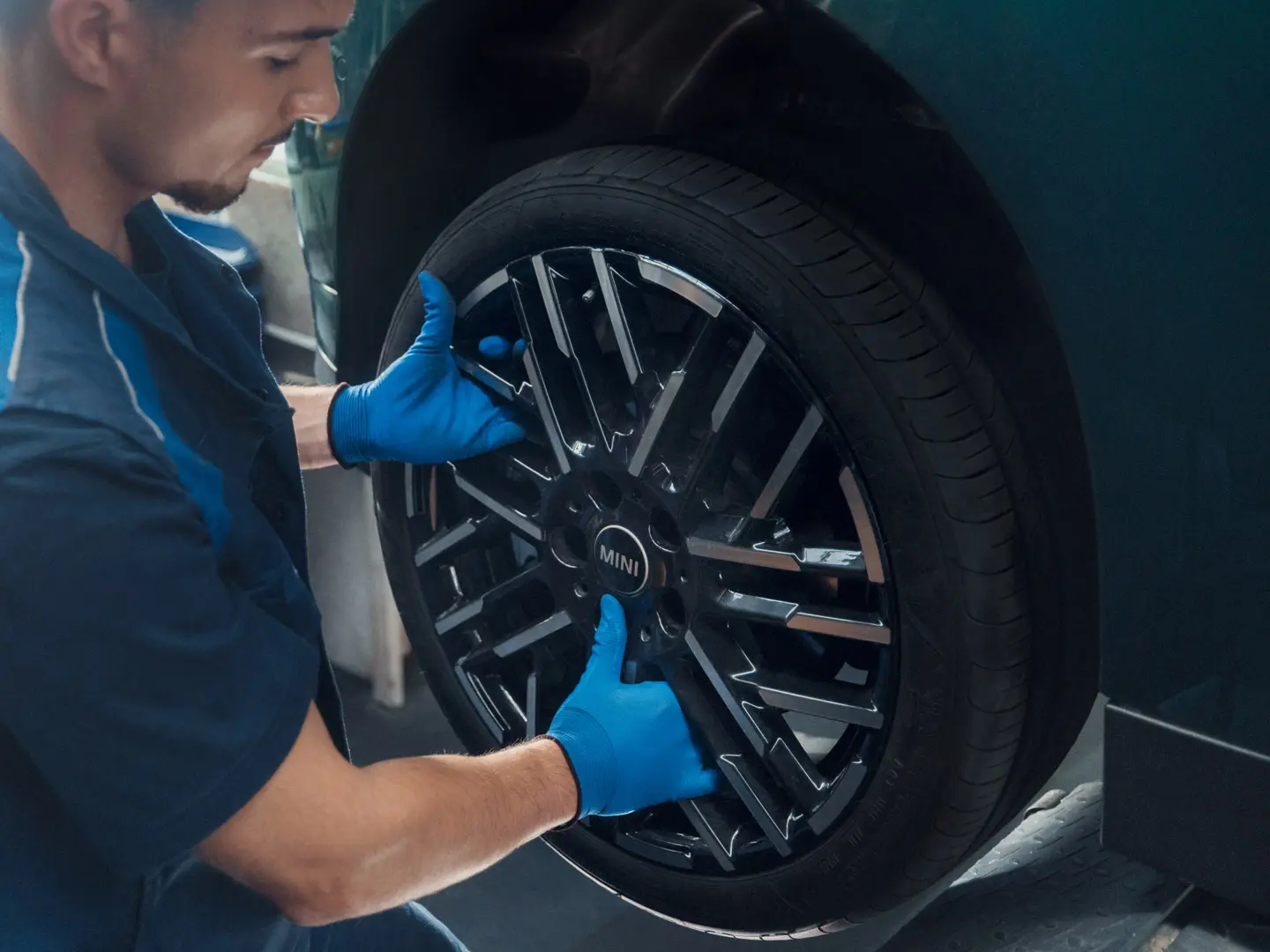 A MINI service technician installs a MINI 18" Night Flash Spoke Bicolour Light Alloy Wheel on a MINI Cooper Electric.