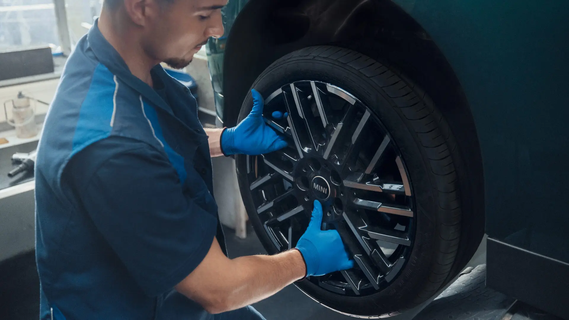A MINI service technician installs a MINI 18" Night Flash Spoke Bicolour Light Alloy Wheel on a MINI Cooper Electric.