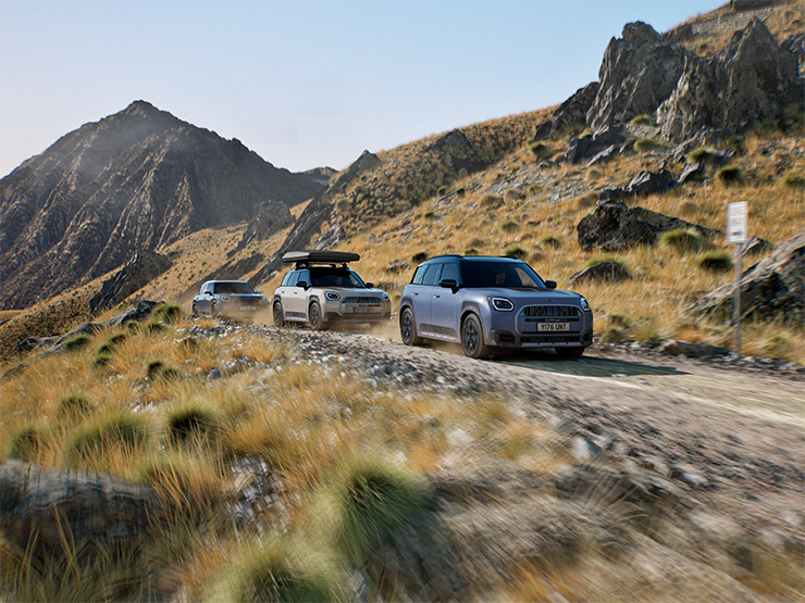 Image of multiple MINI Countryman Untamed Edition models driving on a rugged mountain road.