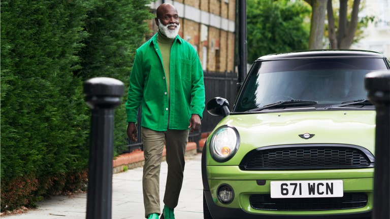 Man with green shirt walking next to a green MINI