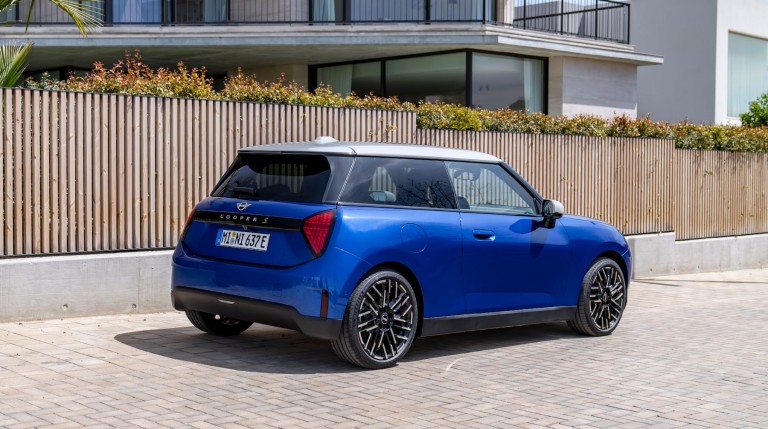 all-electric MINI Cooper rear and side parked outside house next to fence