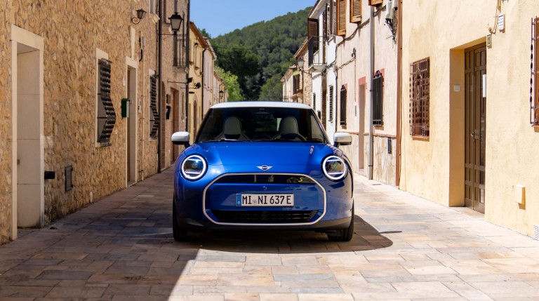all-electric MINI Cooper front view on street buildings either side