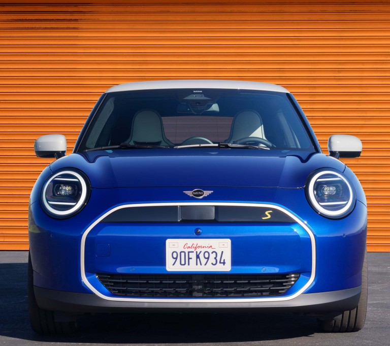 all-electric MINI Cooper front view in front of orange garage door