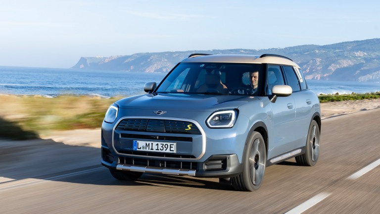 all-electric MINI Countryman driving down road near hills and water